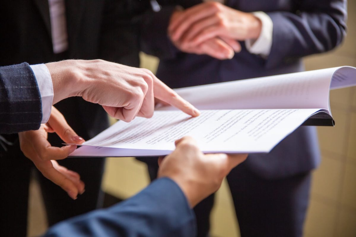 Advogados analisam cláusulas de contrato impresso em folha branca