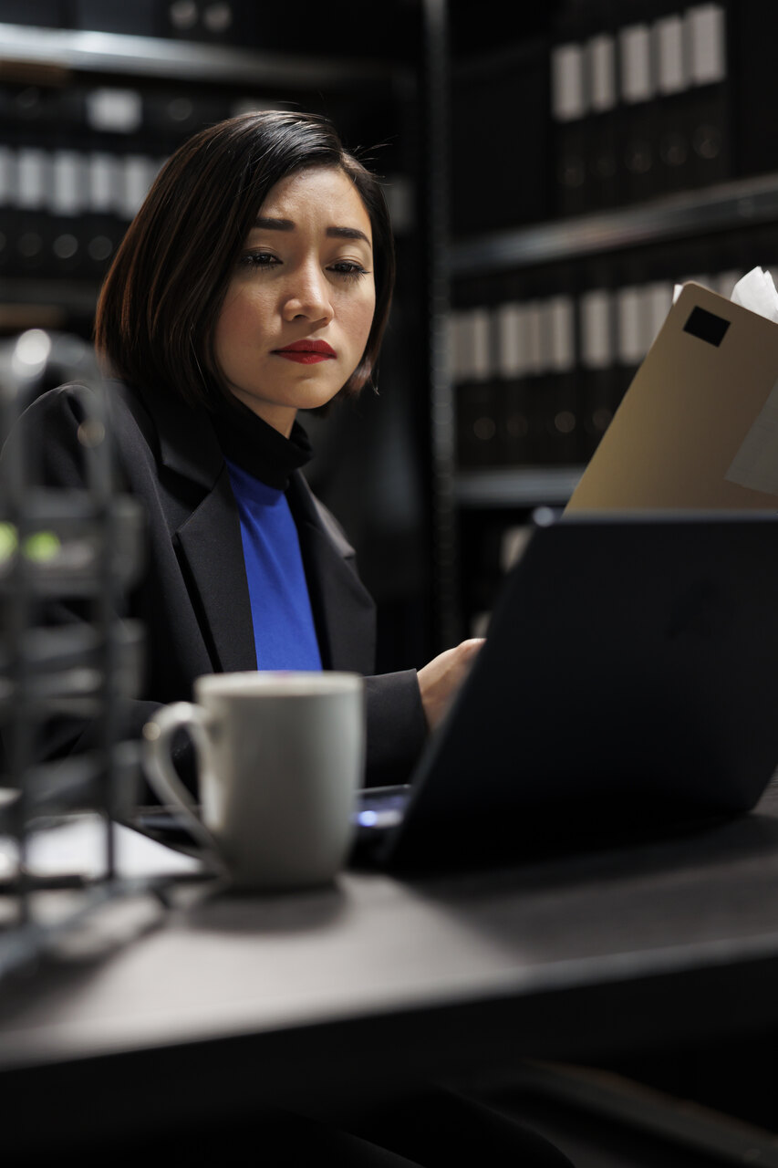 Provimento 205 OAB: advogada sentada em escritório analisando papéis e notebook